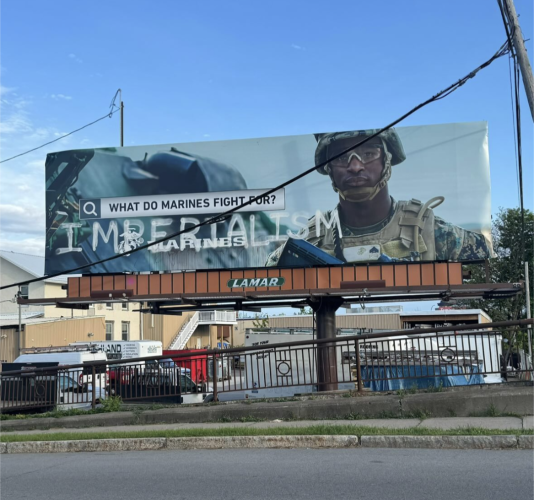 Billboard featuring a soldier and the words "What do marines fight for?"
and "IMPERIALISM" is written under it with chrome spray paint