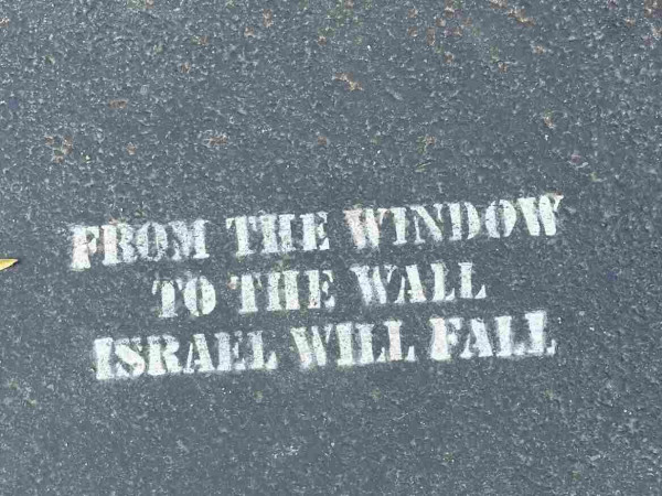White stencil on the ground that says "From the window, to the wall, Israel will fall"