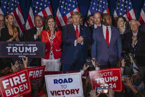 Donald Trump surrounded by supporters and American flags at a campaign event