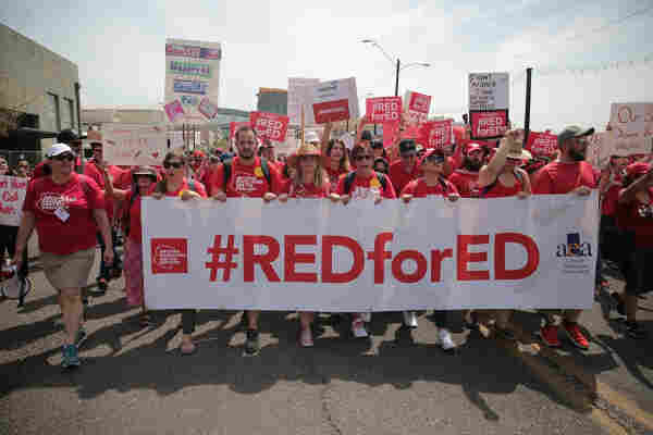 Striking teachers and supporters, wearing red shirts, with a banner that reads “#REDforED.”