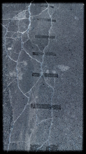 A somewhat abstract image of a section of pavement, dark gray but with meandering white cracks. Moving up the centre of the image are a series of black lines, roughly parallel, as if someone tried to bandage the pavement back together.