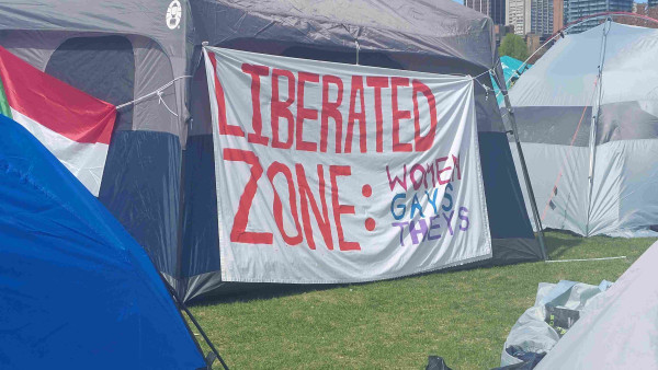 A banner on the side of a large tent reads:

Liberated Zone:
Women
Gays
Theys