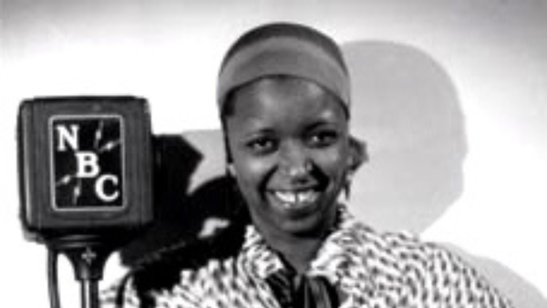 Ethel Waters standing next to an NBR radio mic. She is a black woman with her hair tied back.