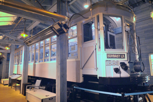 An infrared photo of an old interurban train car, which looks pale pink and appears to have a baby blue interior. It's in a well-maintained-looking shed.