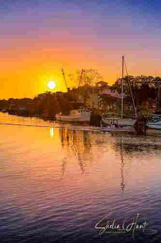 Shem Creek, South Carolina  is absolutely one of the best places to enjoy a beautiful sunrise over the water near Charleston. This photograph was taken just as the sun started to peek up over the horizon, leaving a beautiful orange and pink glow set against the blue sky of early morning. This artwork is from the Fine Art Gallery of Shelia Hunt.