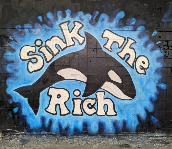 Mural on a black wall of an orca and the words "sink the rich"