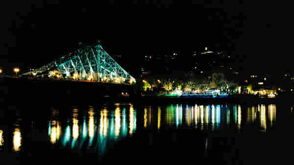 Brücke bei Nacht in Dresden. Lichter spiegeln sich in der Elbe.