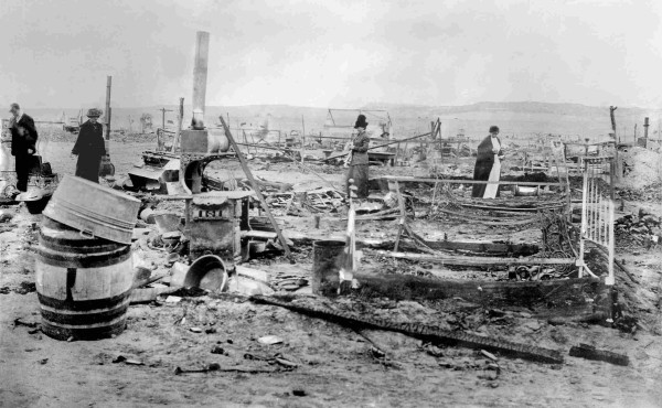 Three women and a man surveying the ruins of the Ludlow Tent Colony in the aftermath of the massacre. Debris, stove pipes, bed frames, a barrel. By Bain News Service - This image is available from the United States Library of Congress&#039;s Prints and Photographs divisionunder the digital ID ggbain.15859.This tag does not indicate the copyright status of the attached work. A normal copyright tag is still required. See Commons:Licensing for more information., Public Domain, https://commons.wikimedia.org/w/index.php?curid=10277066