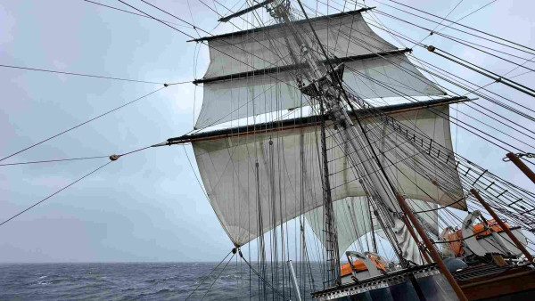 Heeled square rigged ship with upper and lower top sails and courses set. 