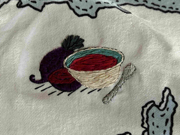 A small embroidered picture of two beetroot and a bowl of beetroot soup 
