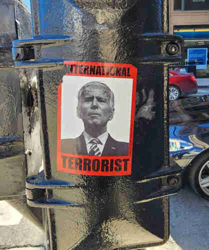 A sticker on a light pole in downtown Chicago. It has a black and white picture of Joe Biden with “International Terrorist” around it.