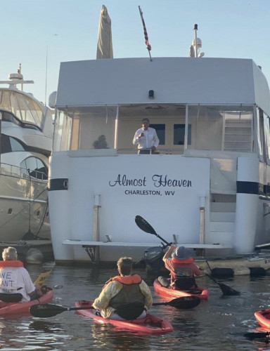 Climate protesters kayak up to Senator Mancin's yacht.
