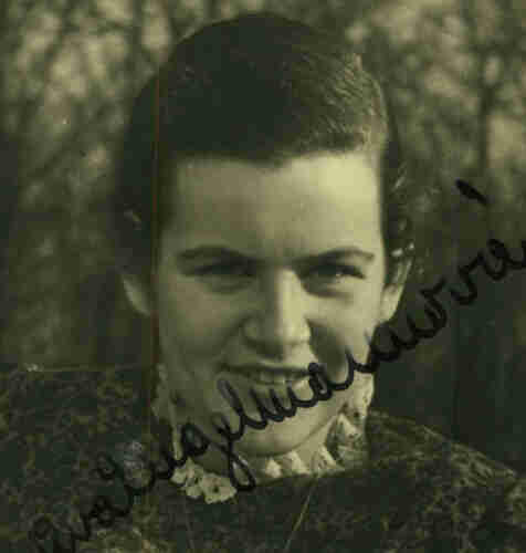 A portrait id photo of a smiling young woman. You can see her head and shoulders. She has dark long hair pinned in the back of her head. Her signature is visible in the photo.