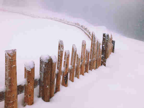 A long fence in the mountain with fog and snow