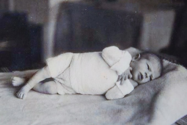 A baby girl lying on a bed. 