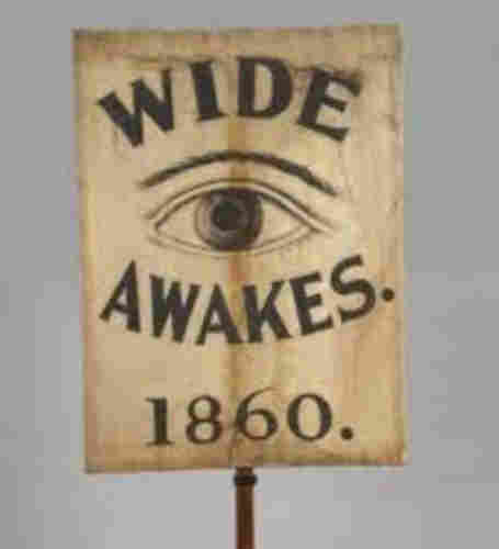 Wide Awakes picket sign that Reads “Wide Awakes,” with an eye between the two words, and the date, 1860, below it. Public domain.