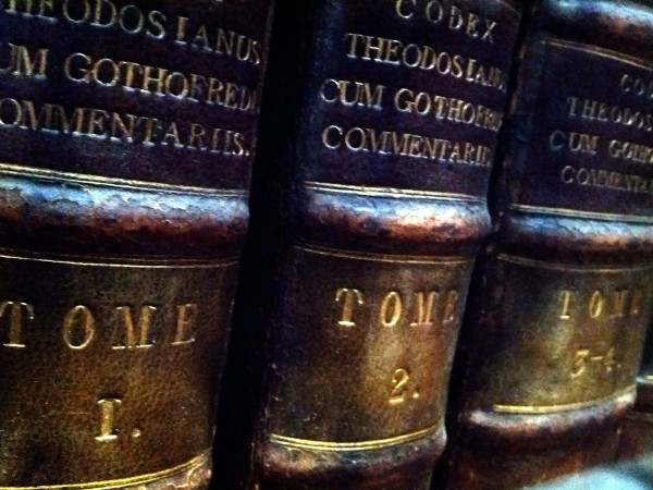 Three antique leather volumes on a shelf. They are three volumes of Codex Theodos Cum, labeled TOME 1, TOME 2, TOME 3–4. Taken at the Royal College of Physicians Library, Regent's Park, London, UK.