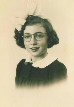 Vintage portrait of a girl with curly hair, wearing glasses and a dark dress with a white collar.
