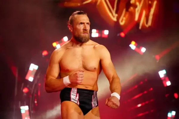 White American pro wrestler, Bryan Danielson, walking from the entrance ramp to the ring. His hair and beard are short and brown, his wrists have white tape on, and his wrestling shorts are black with silver and red flashes running from the legs to the waist.