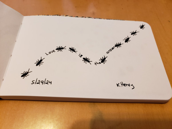 Hand drawn generative/iterative art in ink on an open page of my sketchbook. The abstract pattern has repeating ant motifs as if they are walking on a curving line, with the words "Love is the answer".