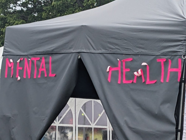 On a tent, the letters for a "Mental Health" label are partially peeling off.