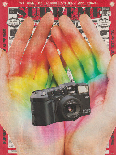 rainbow hands hold a camera with an ad for "SUPREME" camera and video circa 1991 as the background