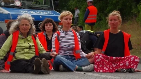 A group of women, scientists and academics, sit on a road in Sweden blocking traffic.