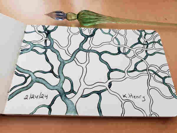 Hand drawn generative art in ink on an open page of my sketchbook. My glass dipping pen is next to my sketchbook. The abstract pattern is a simple branching fractal, like a tree.