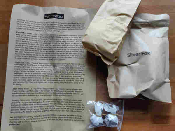 A letter from white2tea printed on unbleached paper, next to 3 tea samples (two brown packets, and a couple of tea balls in a plastic bag)

The letter is too long to type out in its entirety. The three teas are cloud mist green, silver fox white, and 2024 white swan aged raw Puerh.
