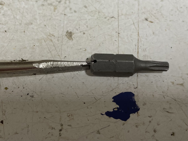 A tamperproof Torx T15 bit with a slot count in it for a straight blade screwdriver. 