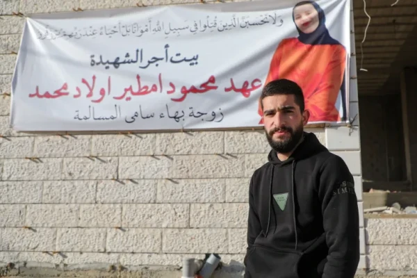 Masalmeh stands in front of a poster with a picture of his wife, Ahed, following her funeral [Mosab Shawer/Al Jazeera]
