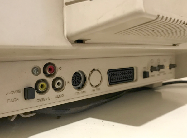 A photo of the ports on the back of a commodore 1084 monitor. Composite, audio, TTL RGB, scart, and a bunch of controls and buttons scattered in between.
