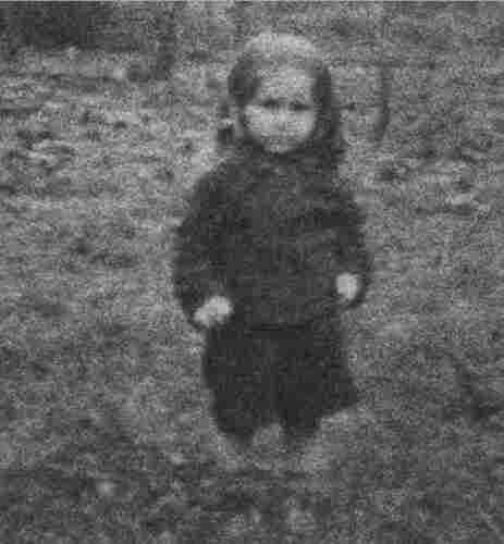A blurry photo of a little boy standing on the grass.