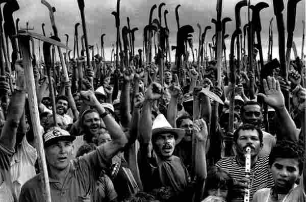 MST March, with peasants carrying scythes and machetes, fists in the air. Photo by Sebastião Salgado.