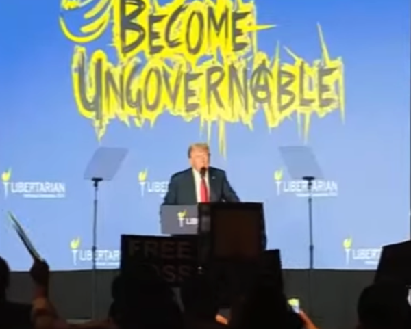 DJT at the Libertarian convention being relentlessly heckled since he failed to seed the crowed enough to keep the Libertarians quiet. 

He's flanked by teleprompters and the "Become Ungovernable" logo... including the anarchist A is behind him. The crowed waved rude signs and some were hauled away by security. 