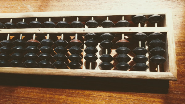 A black and brown soroban-style abacus, where each column is split into to parts: a lower part with 4 beads, each representing a value of 1, and an upper part with 1 bead representing a value of 5. By adding the upper and lower parts together, you get a value between 0 and 9.

As a demonstration, the value currently showing on the abacus is 42,069, presumably in pennies.
