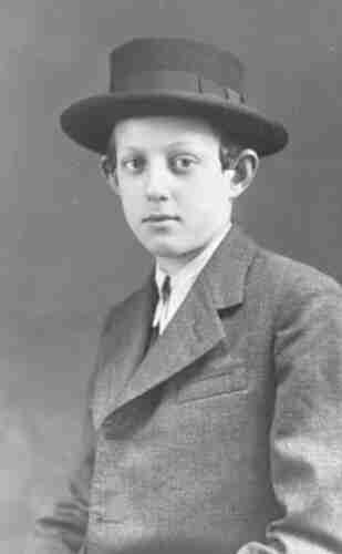 Portrait photograph of a teenage boy wearing a coat, white shirt and hat worn by Orthodox Jews.