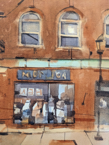 Watercolor painting of a building facade AL ng Main Street in downtown Middlebury, Vermont. A two story brick building takes up the whole scene, with its second story display two arch-topped windows reflection ng back an overcast sky from its drawn shades. The ground floor has a large storefront window with alternating reflections from buildings and sky across the street - behind the viewer - and merchandise. A mint green band of flashing separates the two stories above a blue and gold store sign.